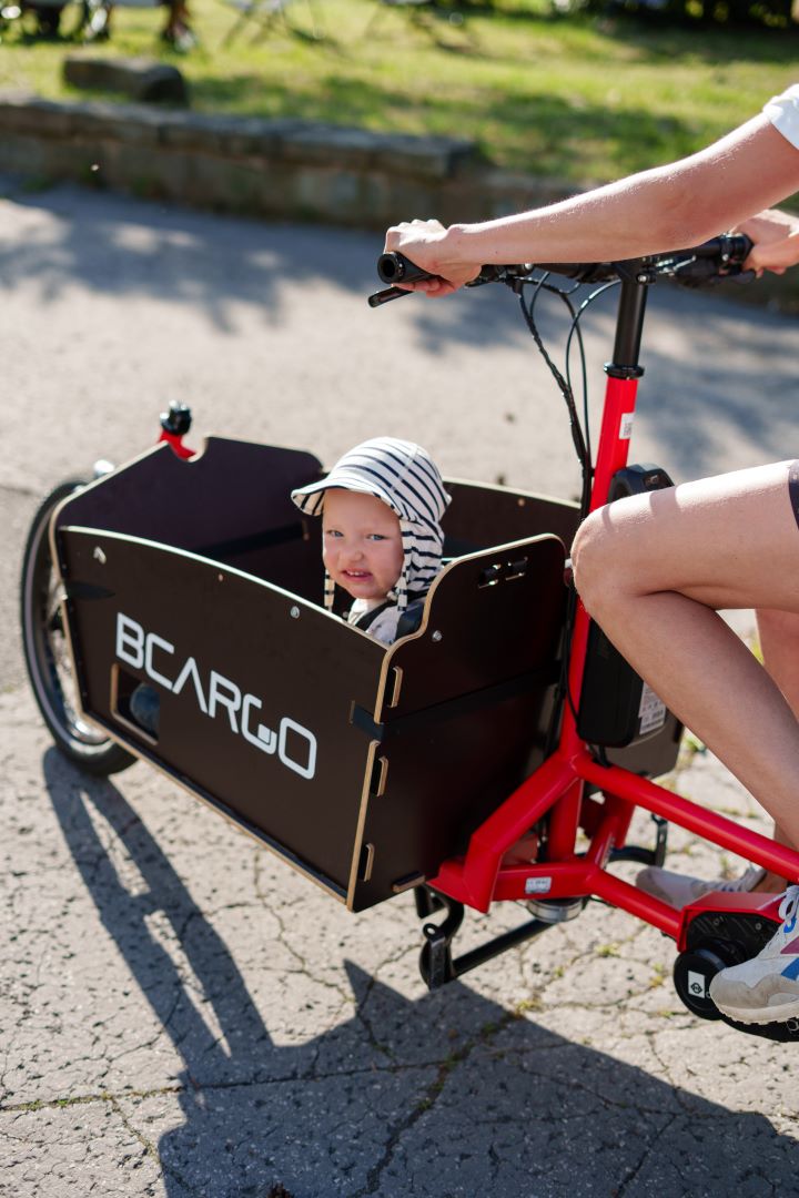 kid in a cargo bike with hat